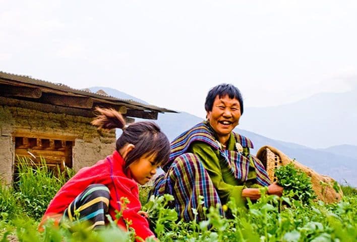 Bhutanese woman and child farming together, symbolizing organic agriculture integration, admired by the explorers.